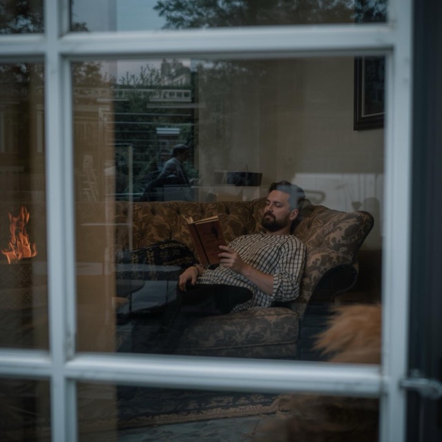 man sitting on couch reading book