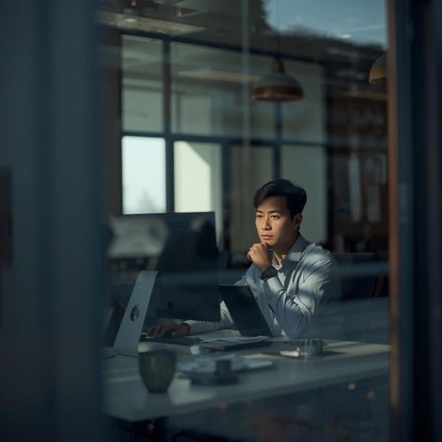 worker at desk in office building, looking at them through the window (3) Medium worker at desk in office building, looking at them through the window