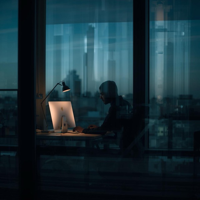 worker at desk in office building, looking at them through the window Medium worker at desk in office building, looking at them through the window
